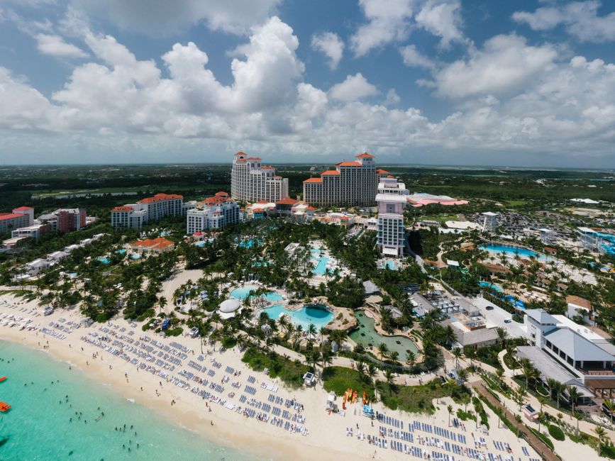 A stunning aerial shot of a luxury resort by the beach in the Bahamas, featuring pools and palm trees.