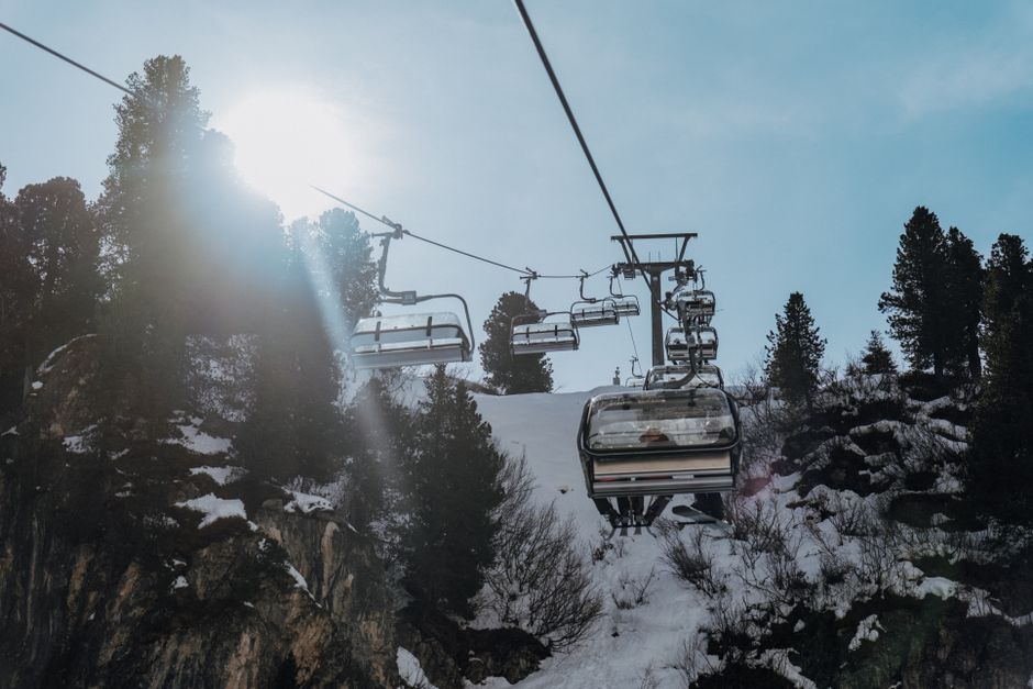 A ski lift ascending a snowy mountain slope under a sunny sky in the Alps.