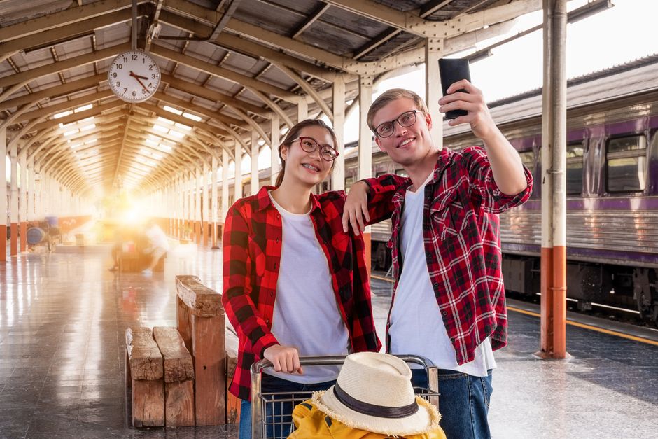 Young couple taking a selfie at an urban train station platform.