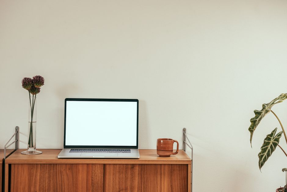 A clean, minimalist workspace with a laptop and coffee mug on a wooden desk for productivity.