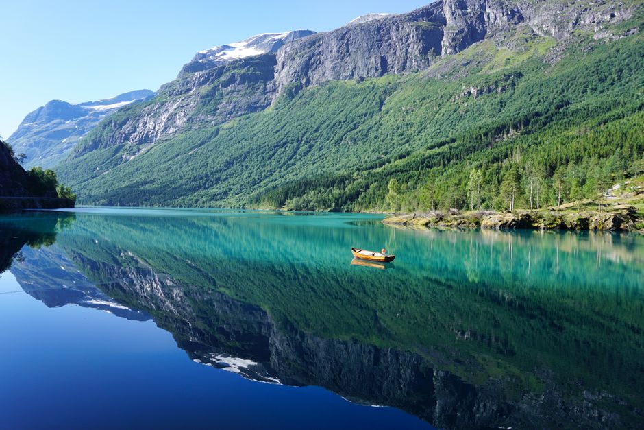Calm turquoise fjord water reflecting steep Norwegian mountains