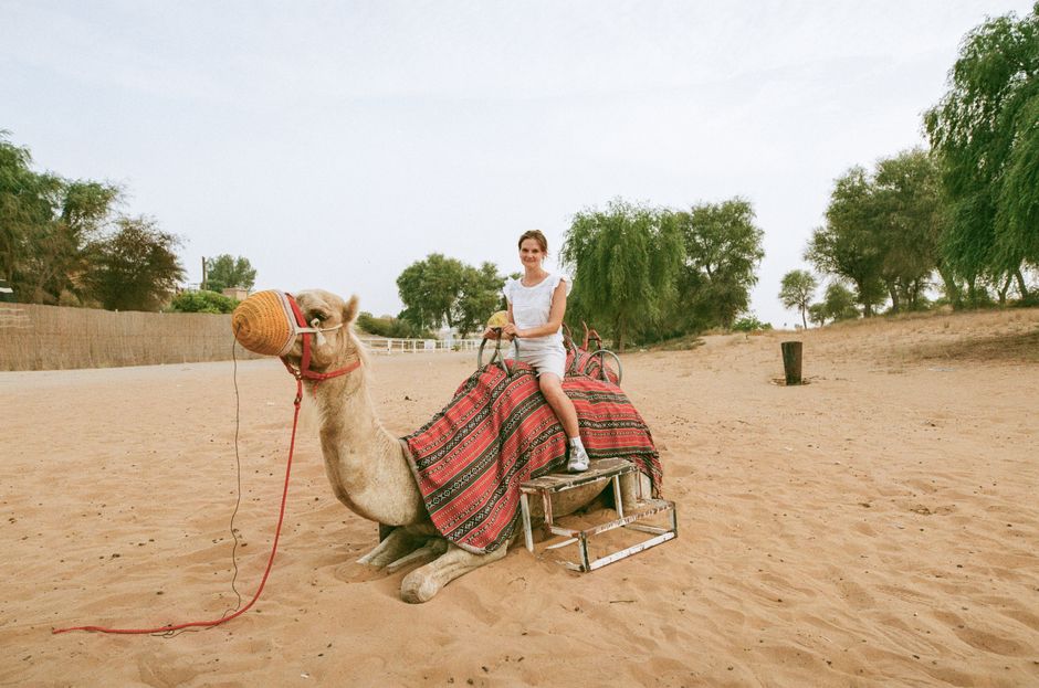A woman riding a camel in the desert of Ras Al-Khaimah, UAE, showcasing the unique desert landscape.