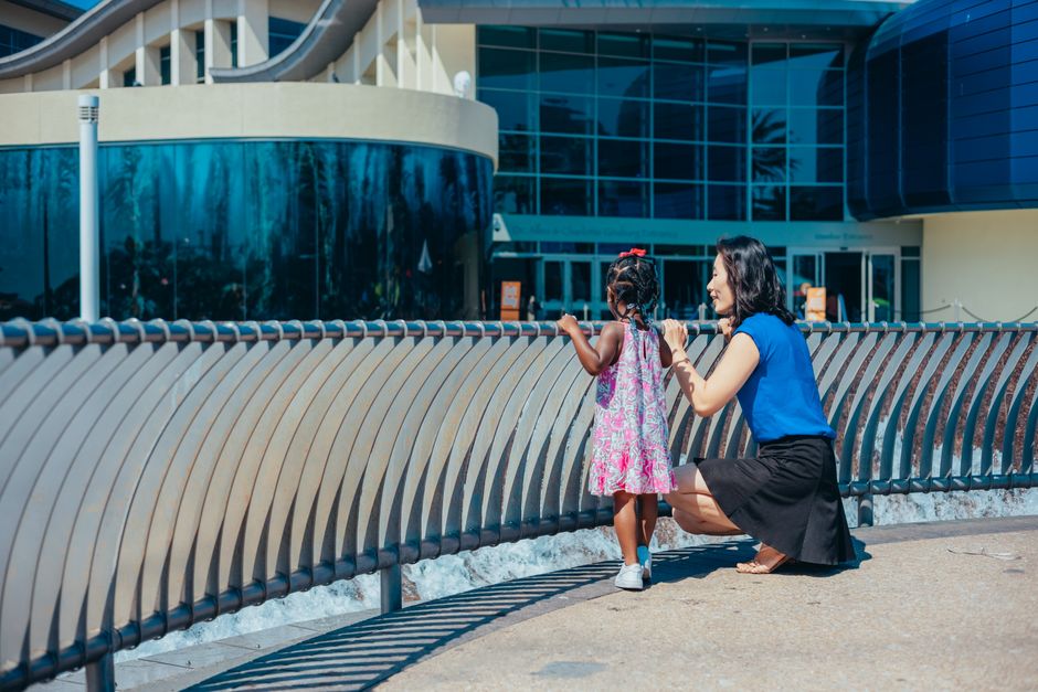 Asian mother and black child enjoying a sunny day outside a modern building.