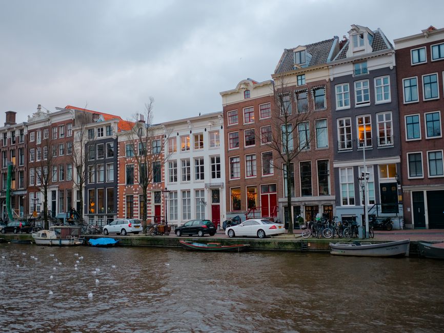 Picturesque view of traditional canal houses in Amsterdam with parked bikes and boats.