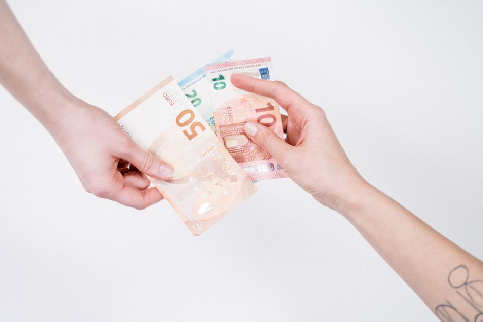 Close-up of hands exchanging euro banknotes, symbolizing financial transactions and currency exchange.