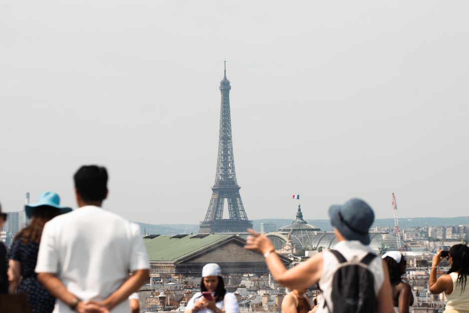 A view of the Eiffel Tower with tourists in the foreground, capturing a sunny day in Paris.