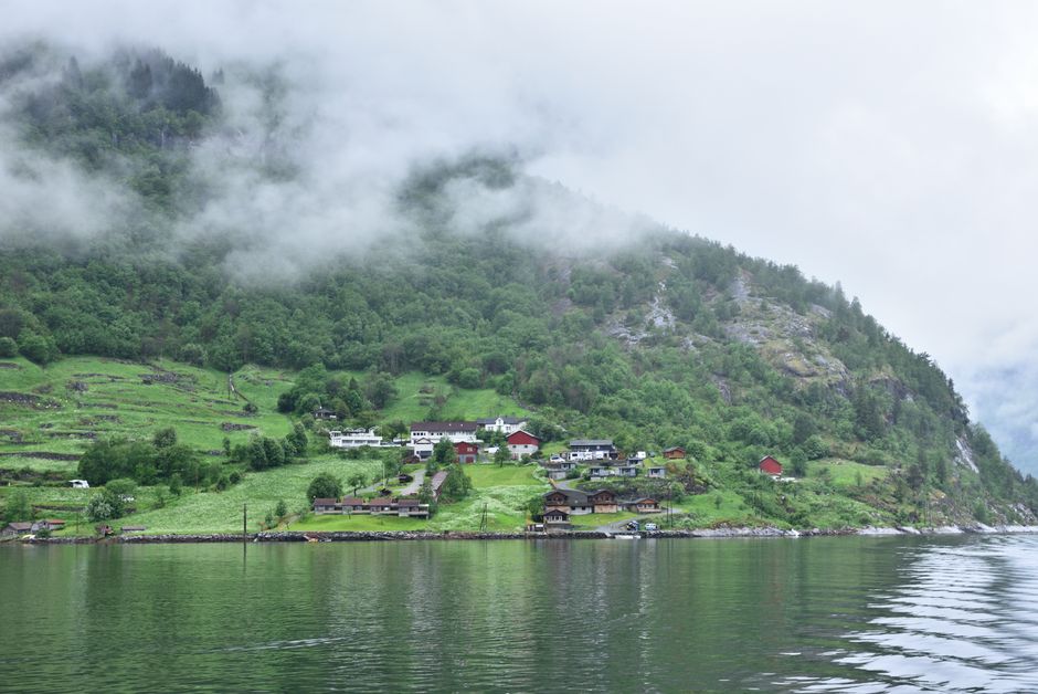 Fjord village beneath misty green mountains in Norway