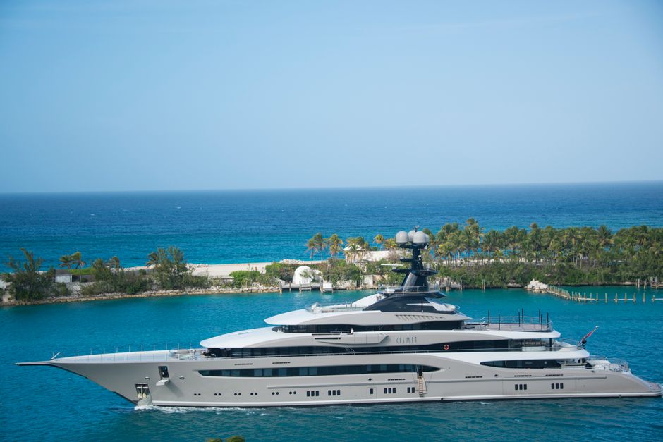 High-end yacht cruising along a tropical coastline with clear blue waters and lush greenery.