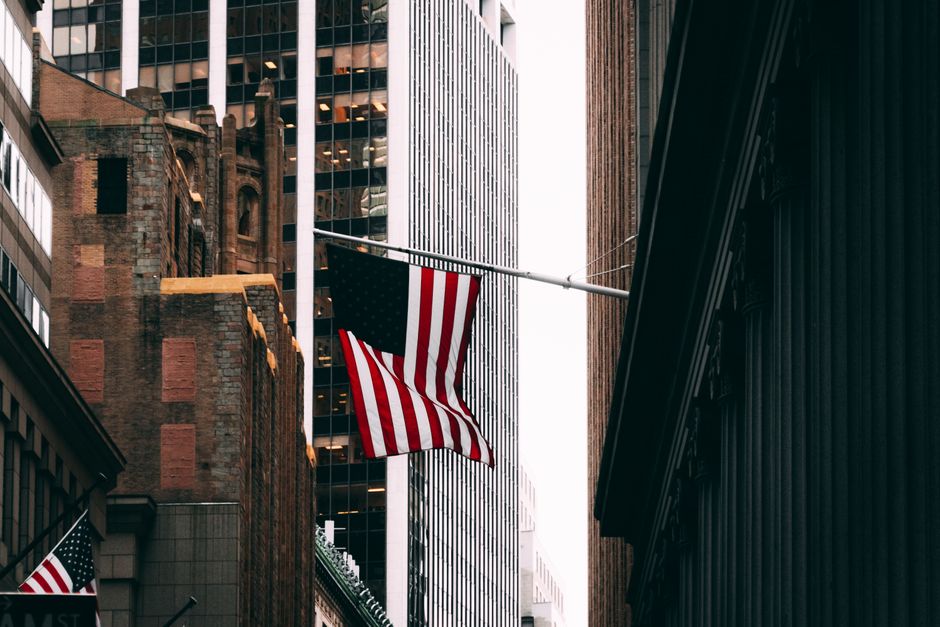 Skyscrapers and American flag in a bustling city financial district street scene.