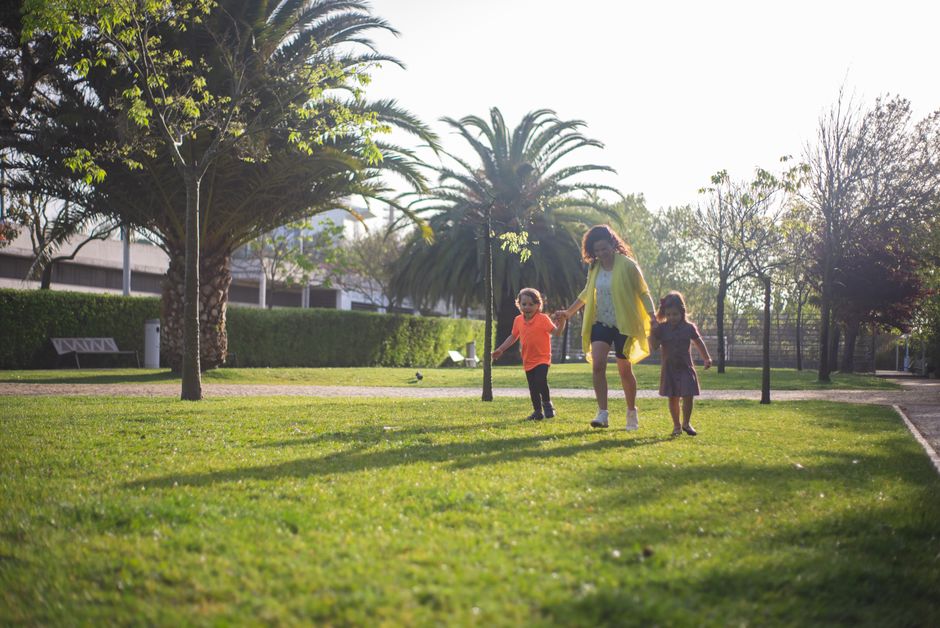 A joyful family enjoys a sunny day walking in a lush green park in Portugal.