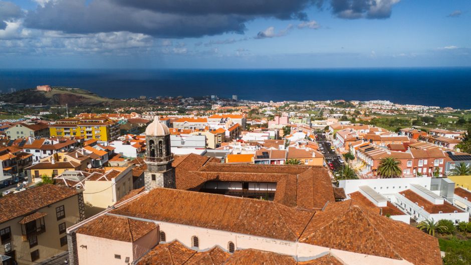 A stunning aerial view of La Orotava town in Tenerife, Spain, showcasing rooftops and the Atlantic Ocean.
