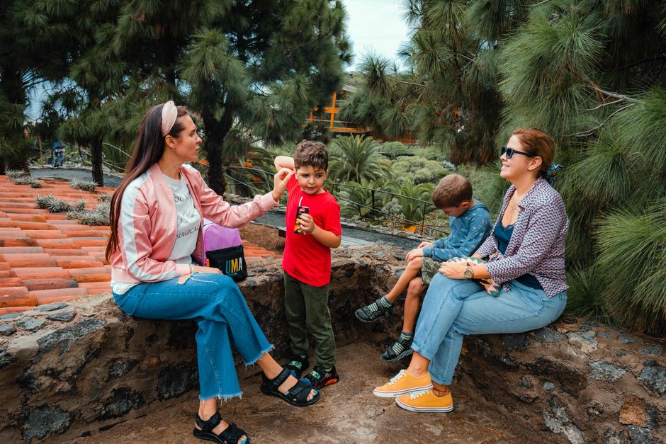 A family enjoys a conversation in a park surrounded by lush greenery and natural beauty.