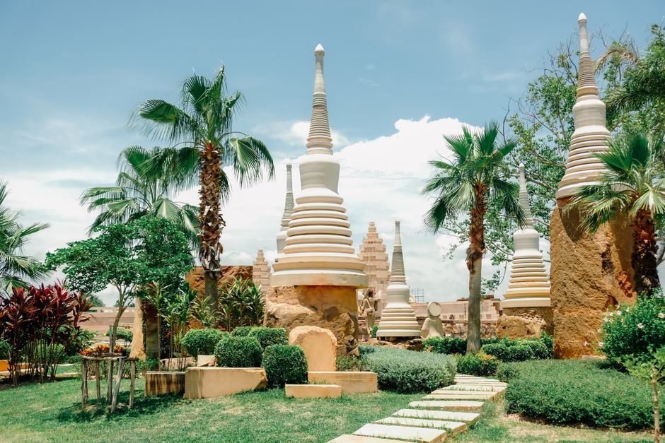 A peaceful garden scene featuring white pagodas and lush greenery under a bright blue sky.