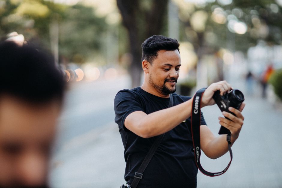 Man taking a photo on a street with a DSLR camera, embodying the art of photography.