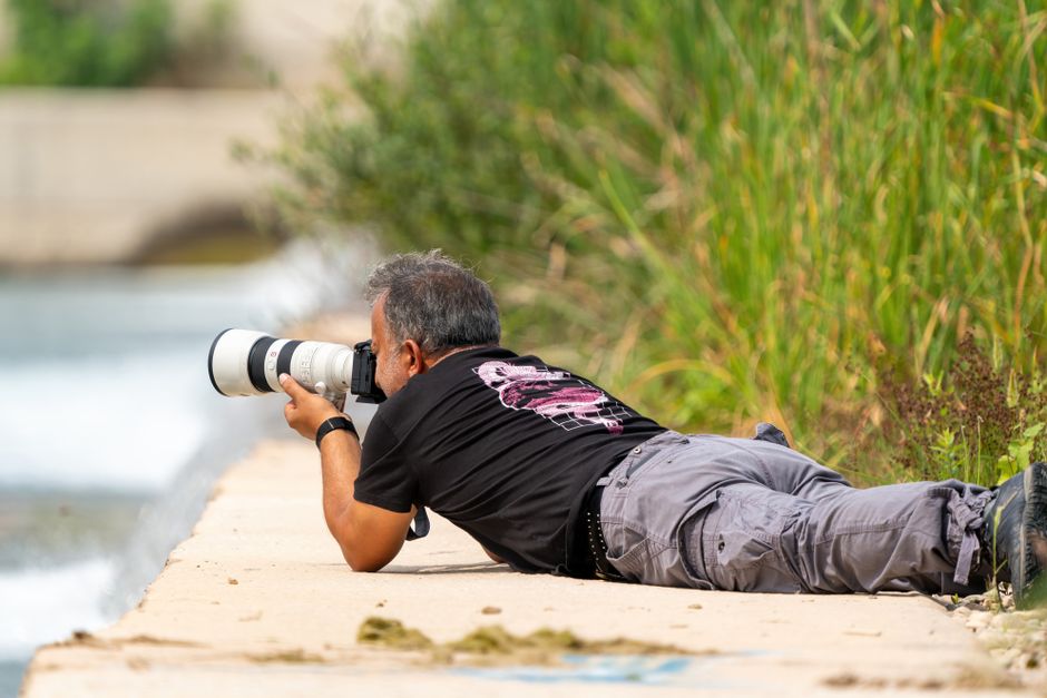 A dedicated photographer lying down capturing a nature shot with a telephoto lens in Antalya, Türkiye.